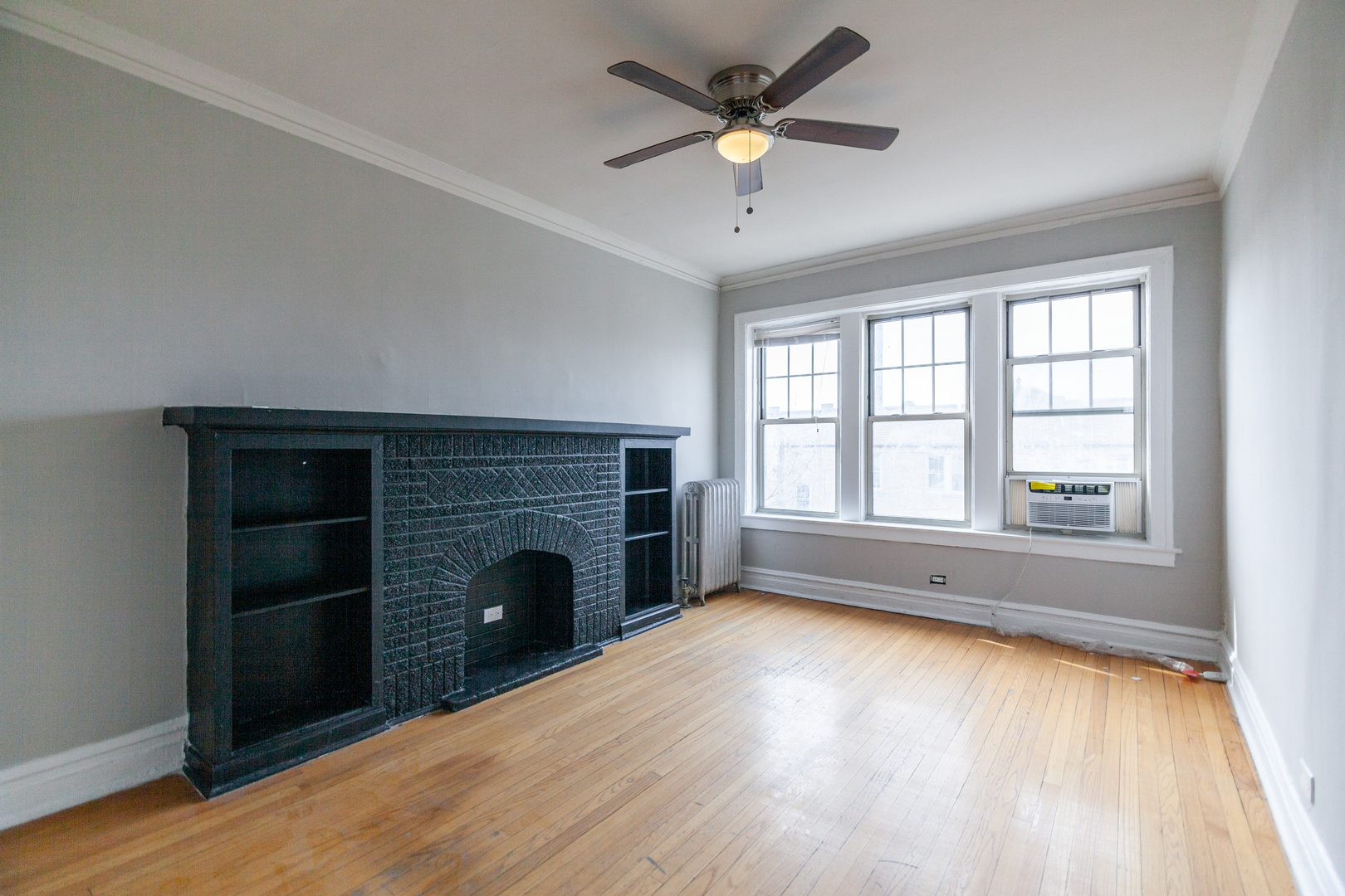 3537 North Troy Street, Unit 3 Chicago, IL 60618 - Photo 2 of 6 an empty room with windows fireplace and wooden floor