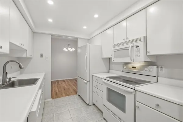 a kitchen with white cabinets and white appliances