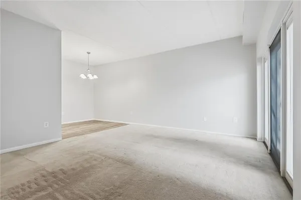 an empty room with a chandelier fan and windows