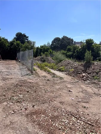a view of a dry yard with wooden fence