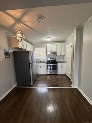 a view of a kitchen with a refrigerator a stove top oven and cabinets