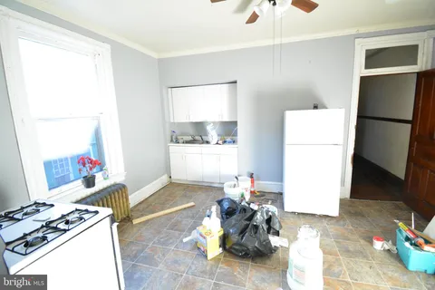 a living room with furniture a refrigerator and a dresser with wooden floor
