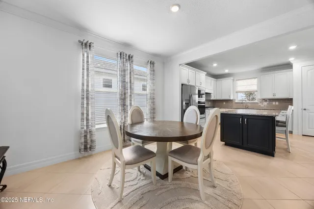 a kitchen with stainless steel appliances granite countertop a refrigerator a stove a sink a dining table and chairs