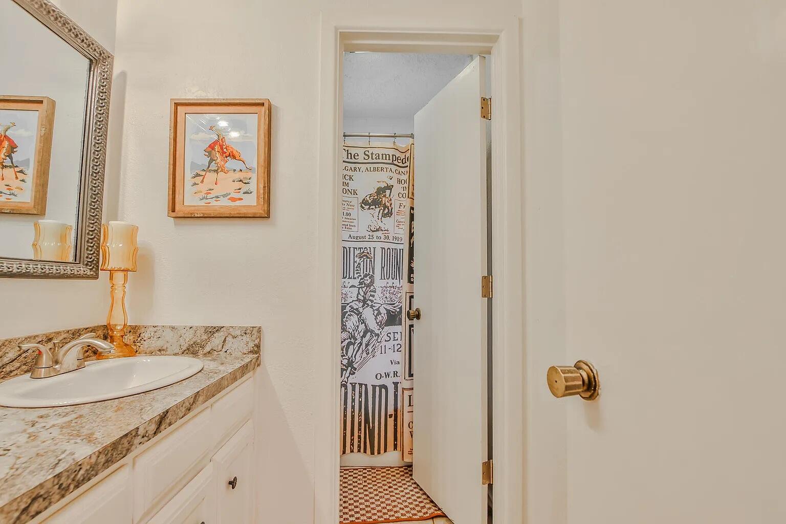 5708 3rd Street Lubbock, TX 79416 - Photo 2 of 23 a bathroom with a granite countertop sink a mirror a vanity and a shower