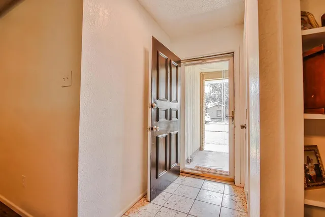 a view of a hallway with wooden floor and a bathroom