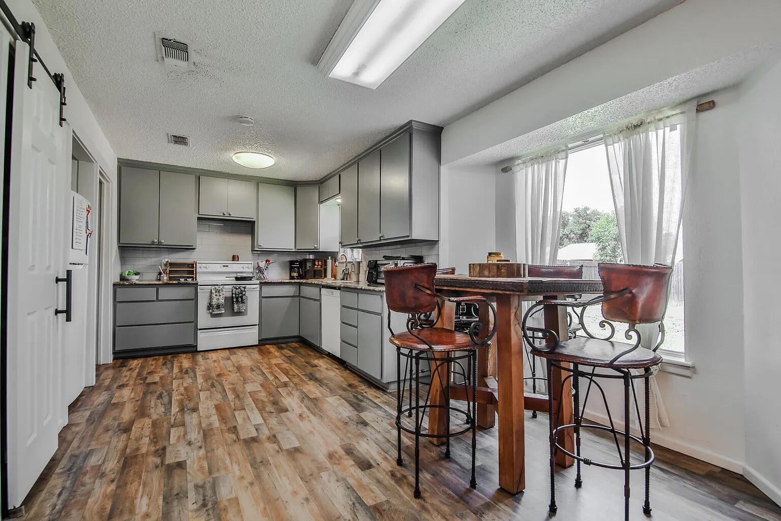 5708 3rd Street Lubbock, TX 79416 - Photo 7 of 23 a kitchen with a table chairs refrigerator and cabinets