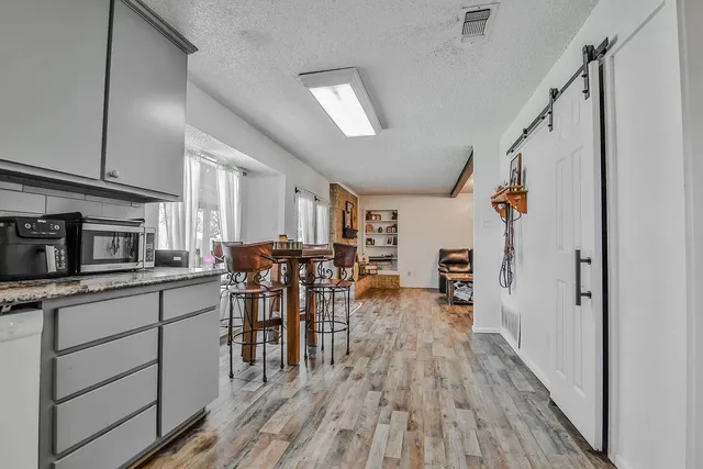 a kitchen with stainless steel appliances granite countertop hardwood floor sink and wooden cabinets