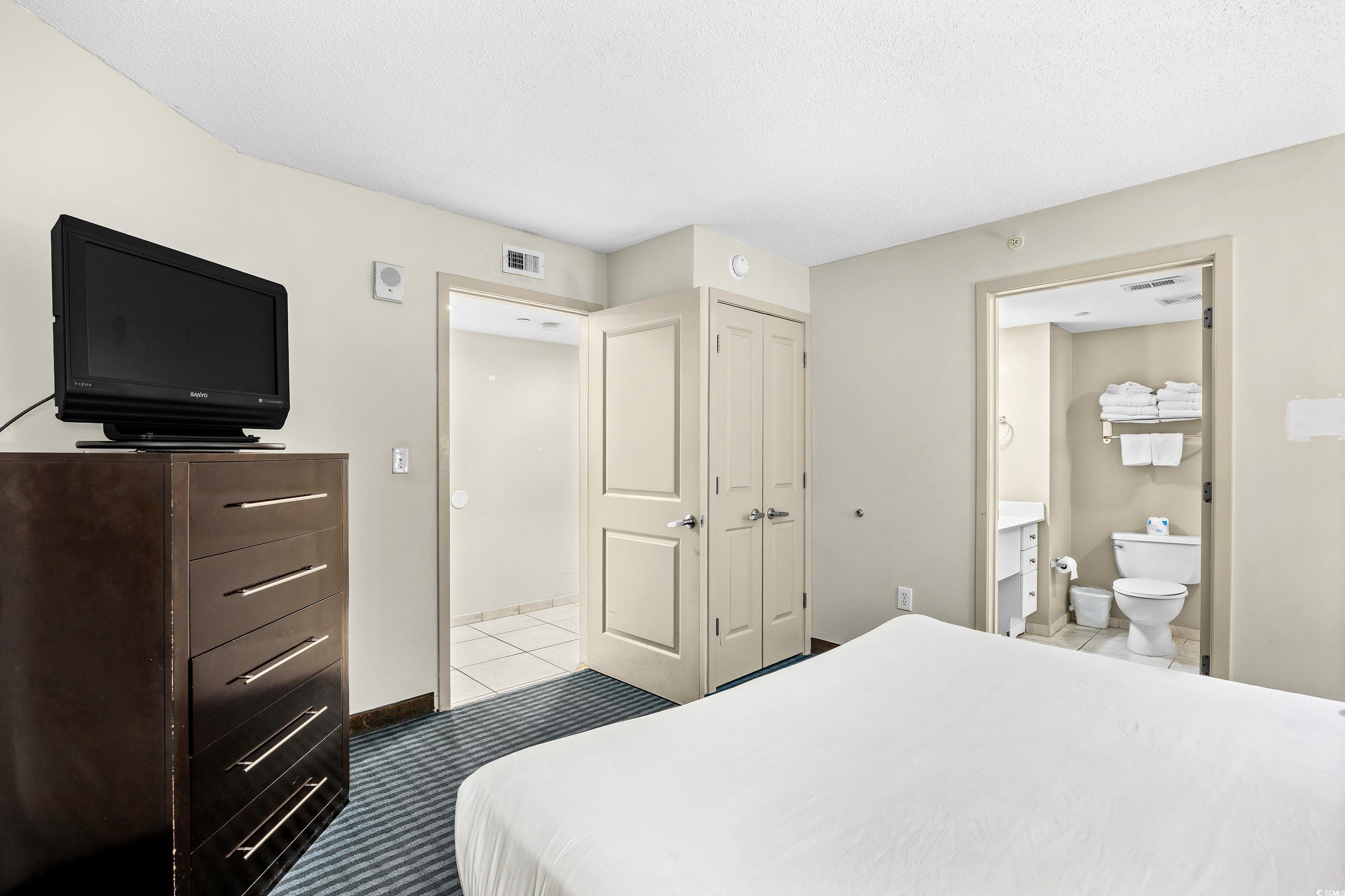 107 Ocean Boulevard, Unit 1402 Myrtle Beach, SC 29577 - Photo 12 of 38 Bedroom with light tile patterned flooring, connected bathroom, a closet, and visible vents