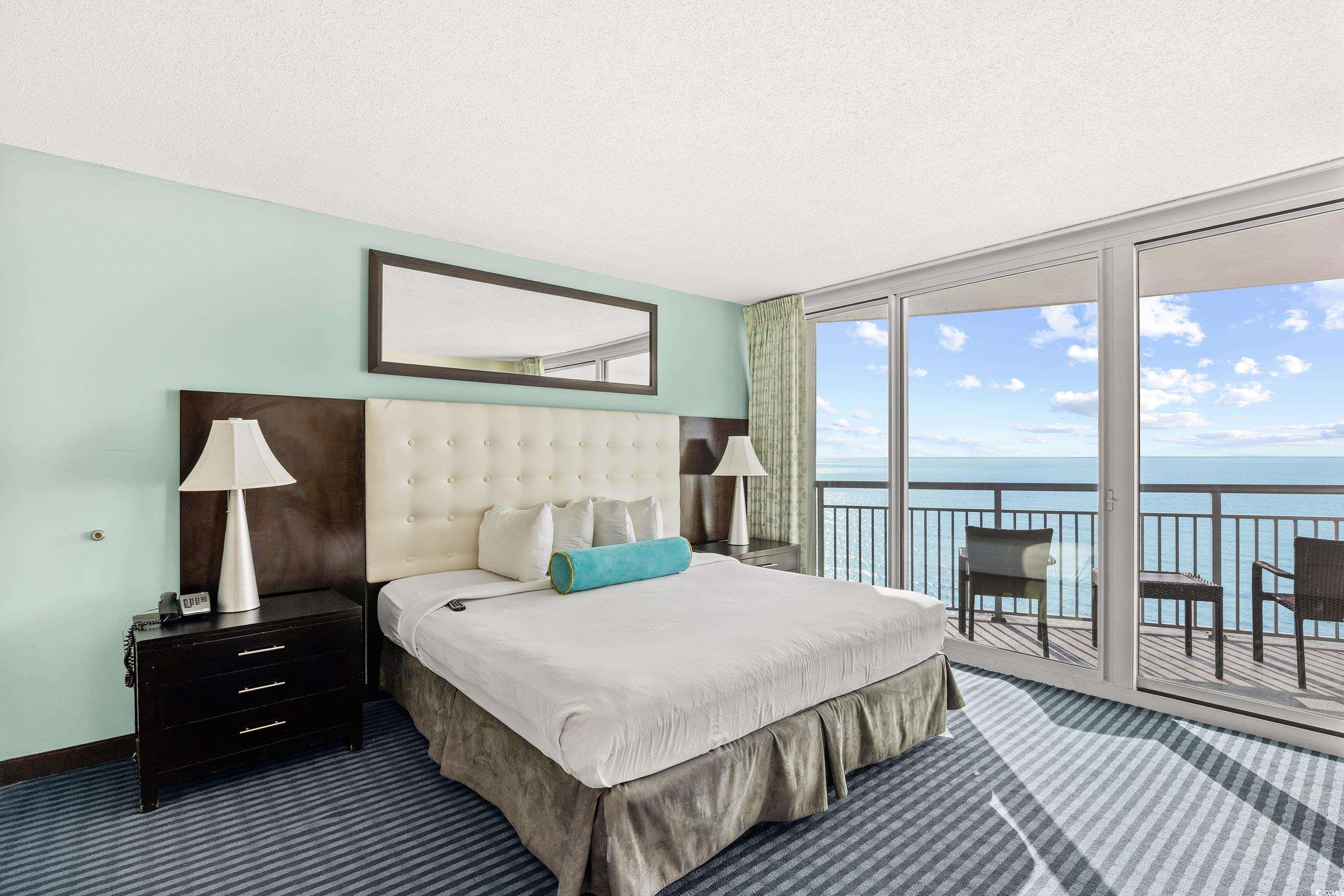 107 Ocean Boulevard, Unit 1402 Myrtle Beach, SC 29577 - Photo 18 of 38 Bedroom featuring a textured ceiling, a wall of windows, a water view, access to outside, and dark carpet