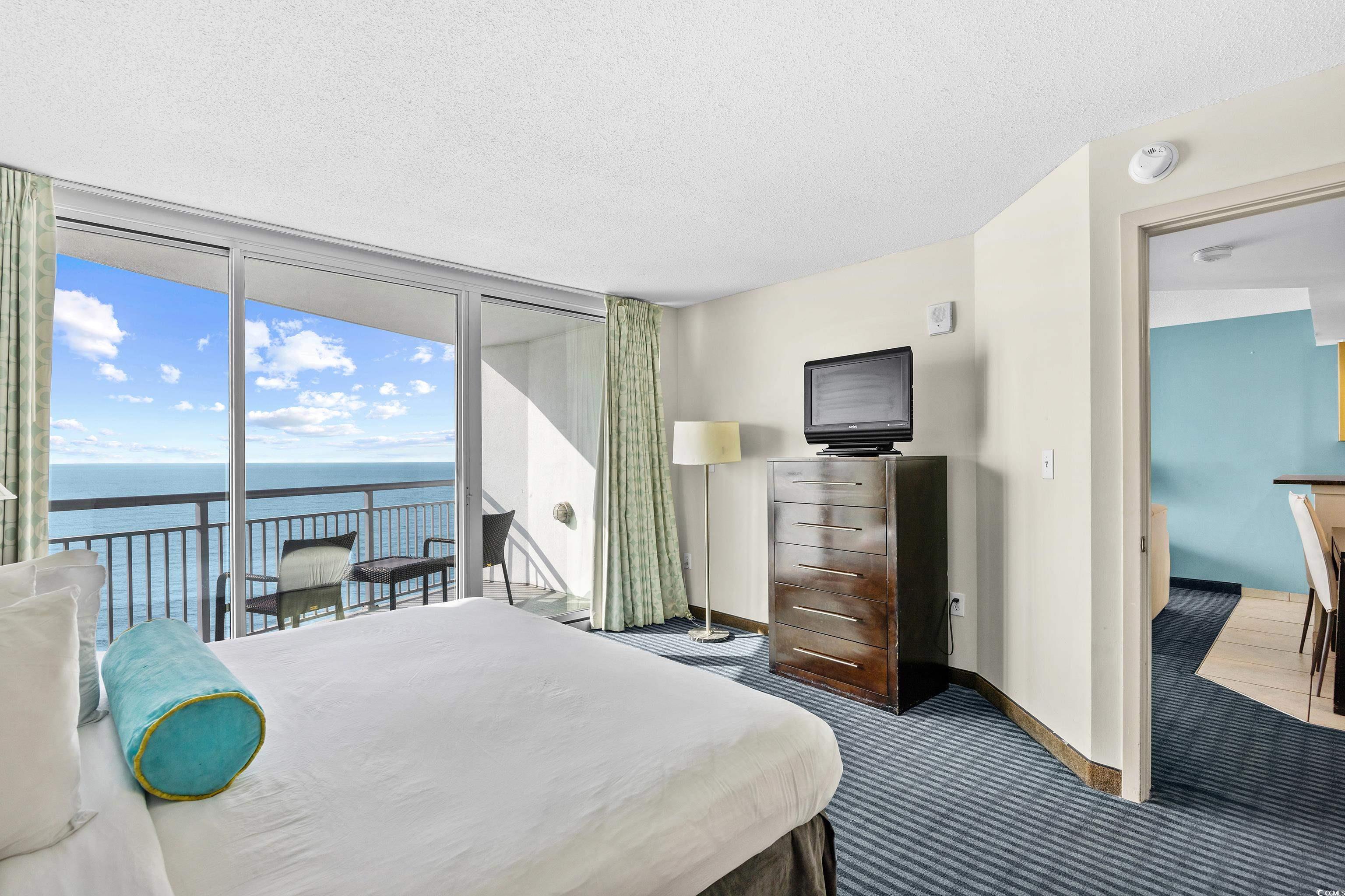 107 Ocean Boulevard, Unit 1402 Myrtle Beach, SC 29577 - Photo 21 of 38 Bedroom with carpet, a water view, access to exterior, expansive windows, and a textured ceiling
