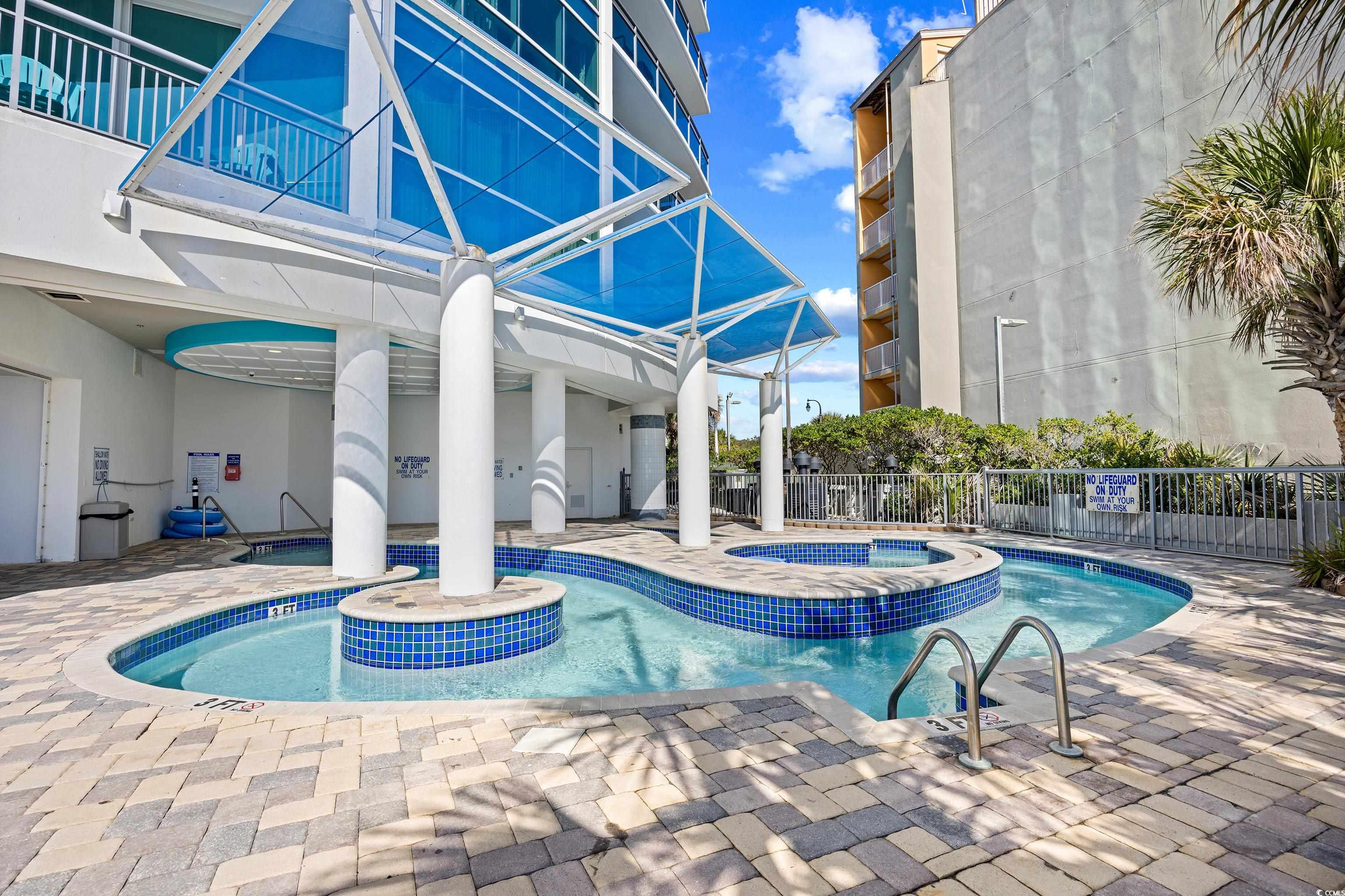 107 Ocean Boulevard, Unit 1402 Myrtle Beach, SC 29577 - Photo 31 of 38 Community pool featuring a community hot tub, fence, and a patio