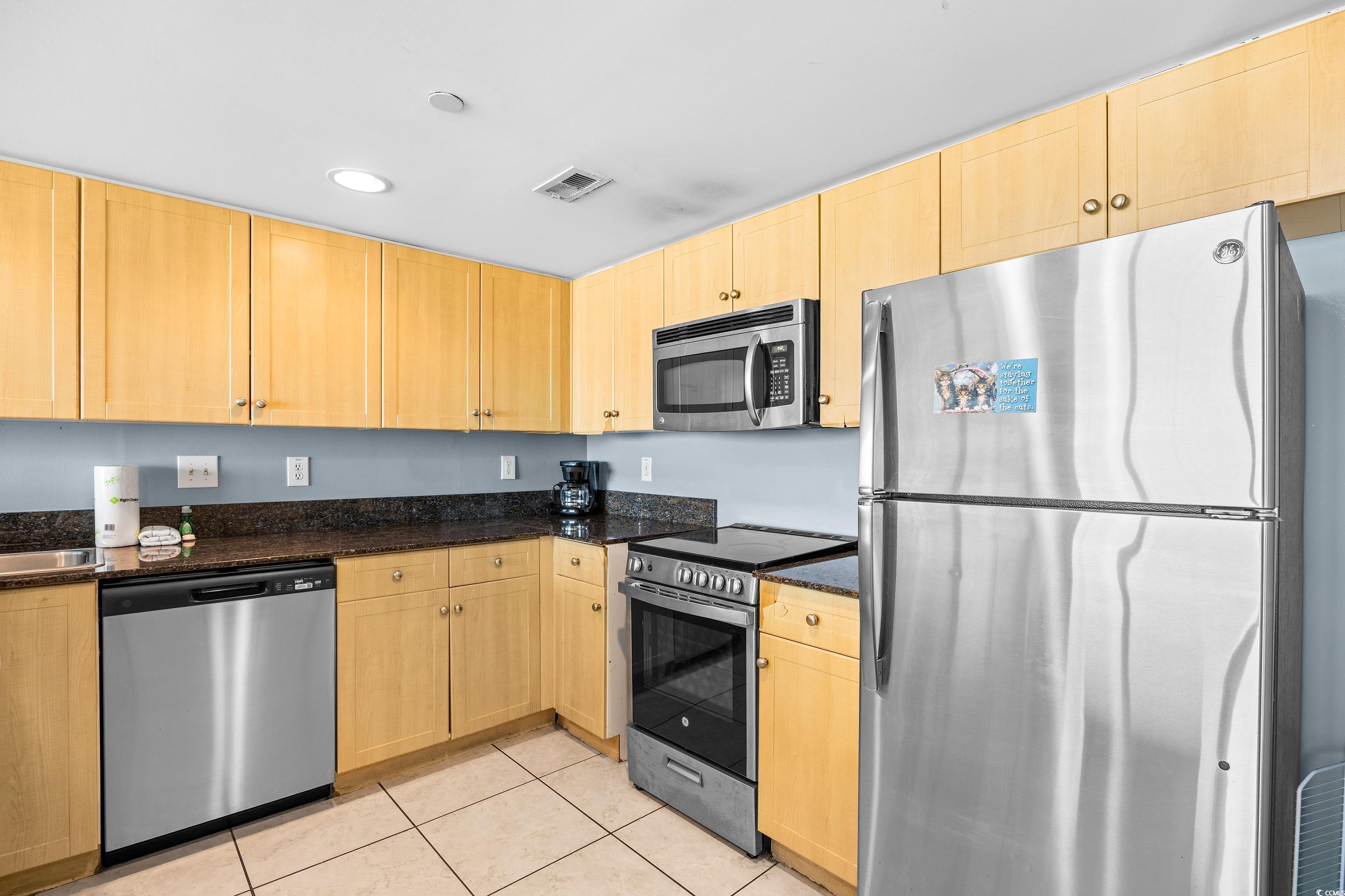 107 Ocean Boulevard, Unit 1402 Myrtle Beach, SC 29577 - Photo 4 of 38 Kitchen with dark stone countertops, light brown cabinetry, visible vents, appliances with stainless steel finishes, and light tile patterned flooring