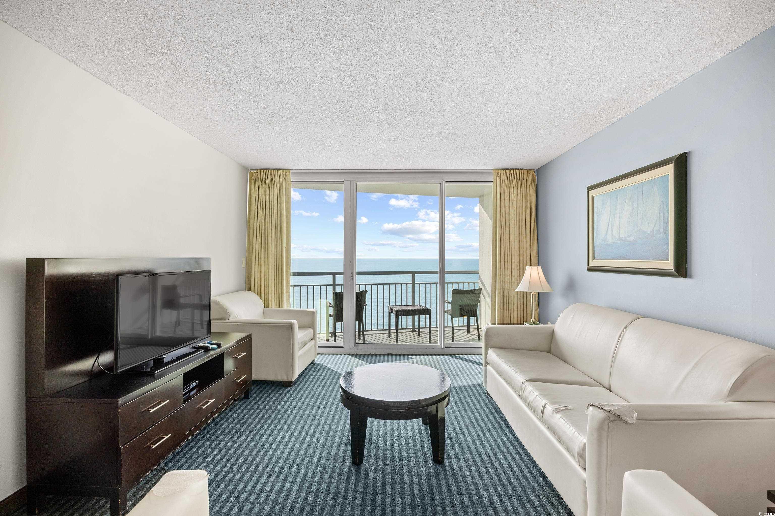 107 Ocean Boulevard, Unit 1402 Myrtle Beach, SC 29577 - Photo 7 of 38 Living area with dark colored carpet, expansive windows, and a textured ceiling