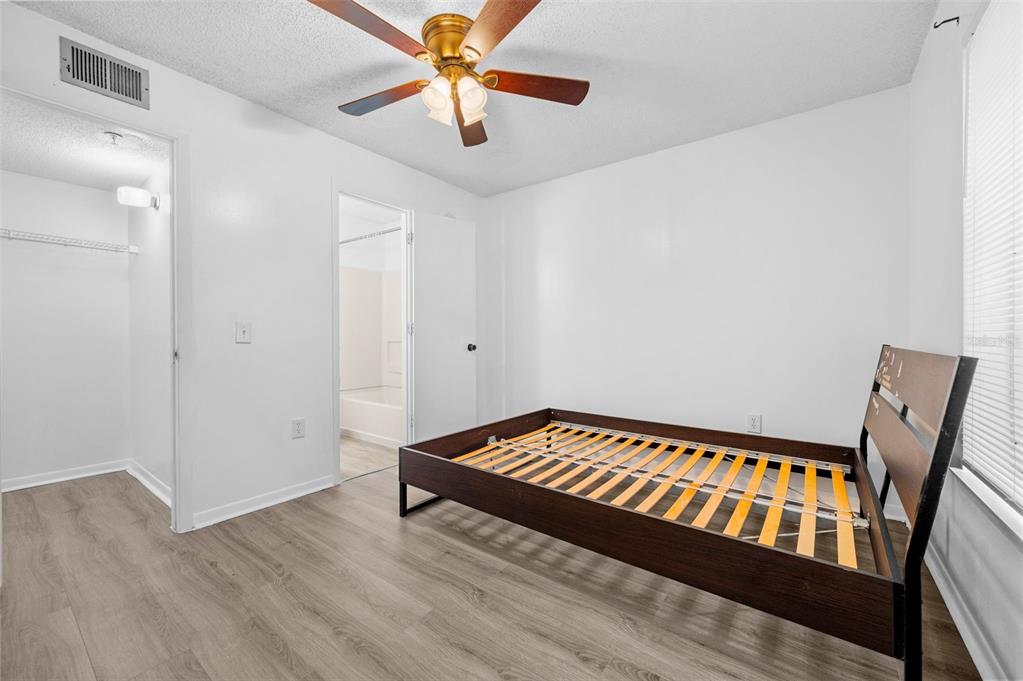 3921 Southwest 34th Street, Unit 208 Gainesville, FL 32608 - Photo 16 of 33 a bedroom with wooden floor and a ceiling fan