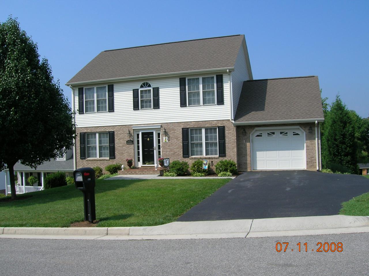 a front view of a house with a yard and trees