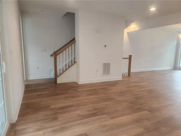 a view of empty room with wooden floor and a window