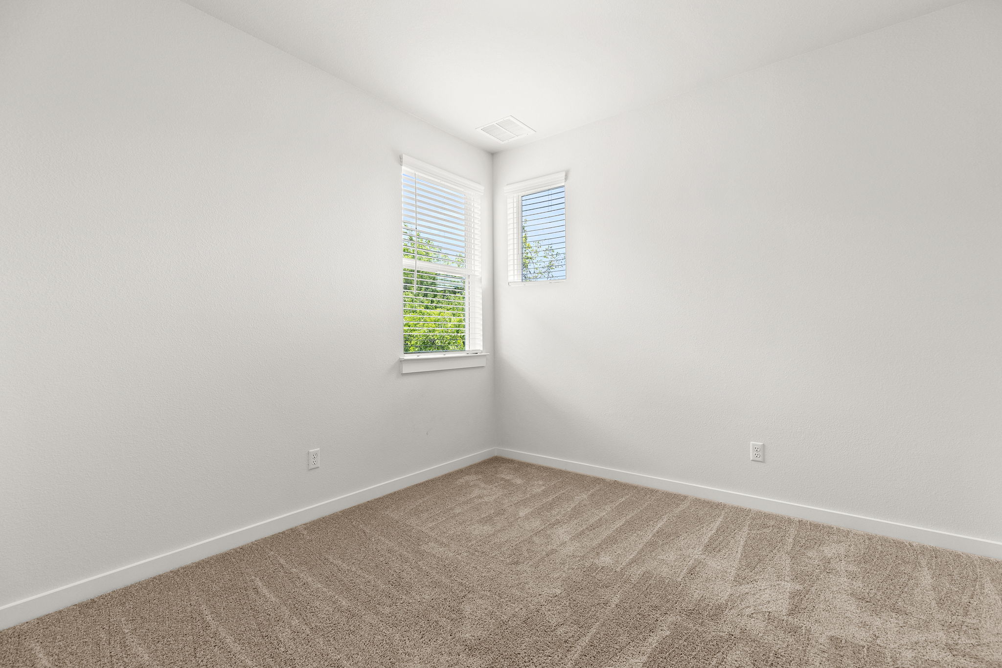 2600 Gattis School Road, Unit 1001 Round Rock, TX 78664 - Photo 26 of 40 Two large windows illuminate this carpeted room, offering serene views of green foliage.