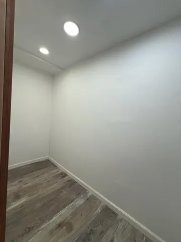 an empty room with wooden floor and fan