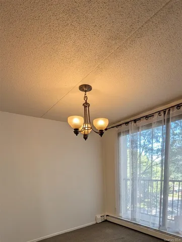 a view of a room with a large window and chandelier fan