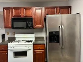 a kitchen with granite countertop a refrigerator stove and microwave
