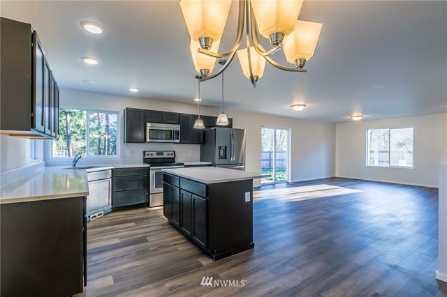 a kitchen with stainless steel appliances granite countertop a sink a stove and a wooden floors