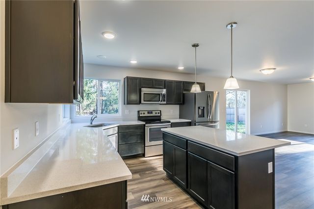 a large kitchen with stainless steel appliances granite countertop a stove and a wooden floors