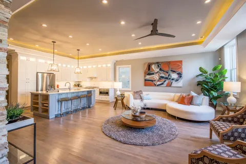 a living room with furniture kitchen view and a large window