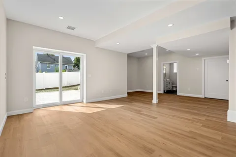 a view of an empty room with a window and wooden floor