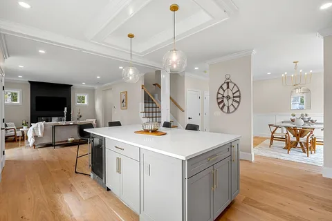 a view of kitchen with kitchen island a sink and a stove top oven with wooden floor