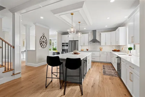 a kitchen with stainless steel appliances kitchen island granite countertop a dining table chairs and a refrigerator