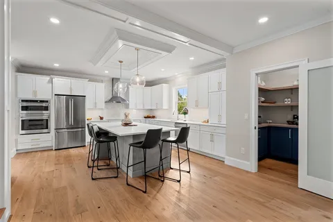 a kitchen with stainless steel appliances a dining table chairs and wooden floor