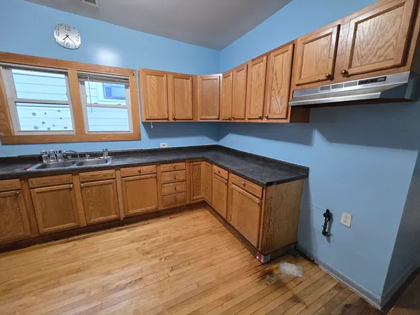 a kitchen with stainless steel appliances granite countertop a sink a stove cabinets and wooden floor