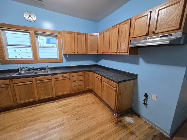 a kitchen with stainless steel appliances granite countertop a sink a stove cabinets and wooden floor