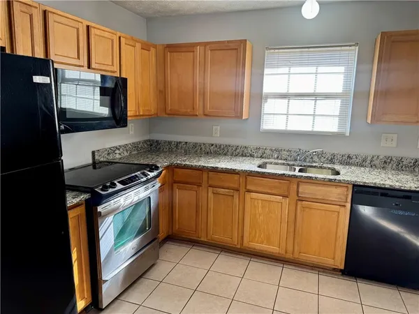 a kitchen with granite countertop cabinets stainless steel appliances a sink and a window