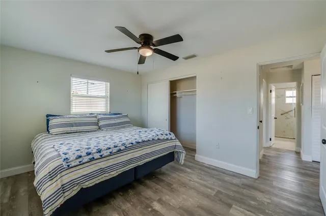 an empty room with wooden floor ceiling fan and windows