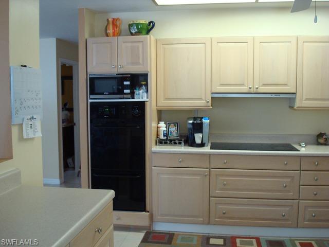 1205 Creech Road Naples, FL 34103 - Photo 7 of 10 a kitchen with white cabinets and refrigerator