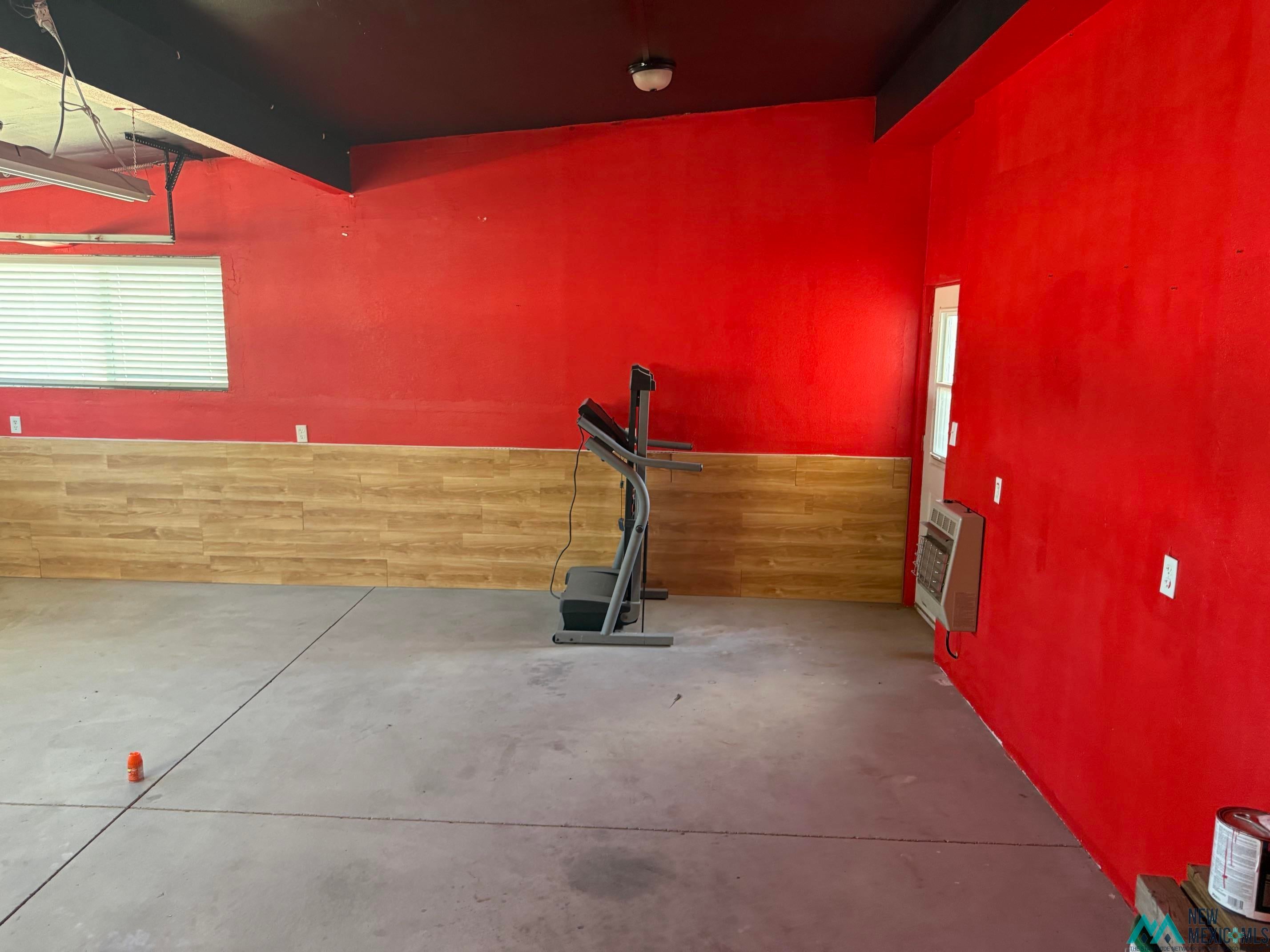 104 Shawnee Road Logan, NM 88426 - Photo 31 of 36 Spacious room featuring concrete flooring and red-painted walls with wood-finish wainscoting