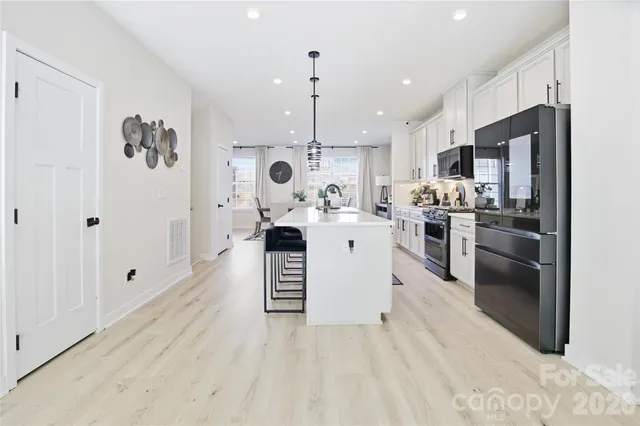 a kitchen with stainless steel appliances granite countertop a refrigerator a stove oven a sink dishwasher and white cabinets with wooden floor