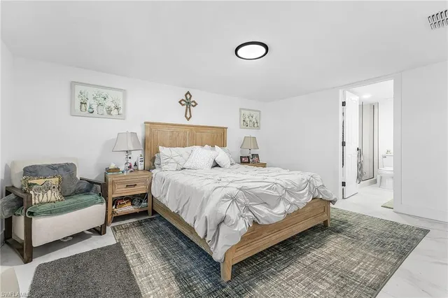 a spacious bedroom with a bed a couch and painting on the wall