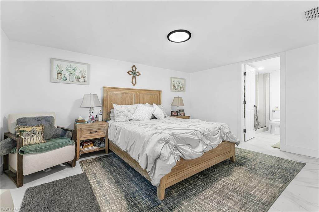 3843 Marvaez Street Fort Myers, FL 33901 - Photo 12 of 26 a spacious bedroom with a bed a couch and painting on the wall