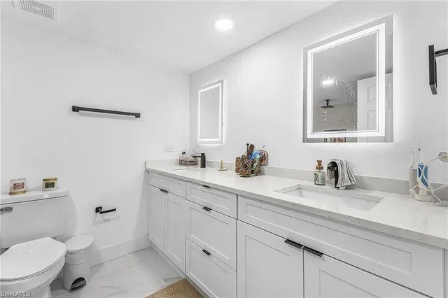 a bathroom with a granite countertop toilet sink double and mirror