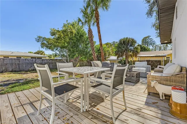 a view of a patio with dining table and chairs with wooden floor and fence