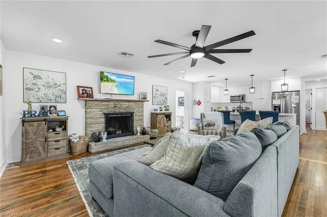 a living room with furniture a fireplace and a ceiling fan