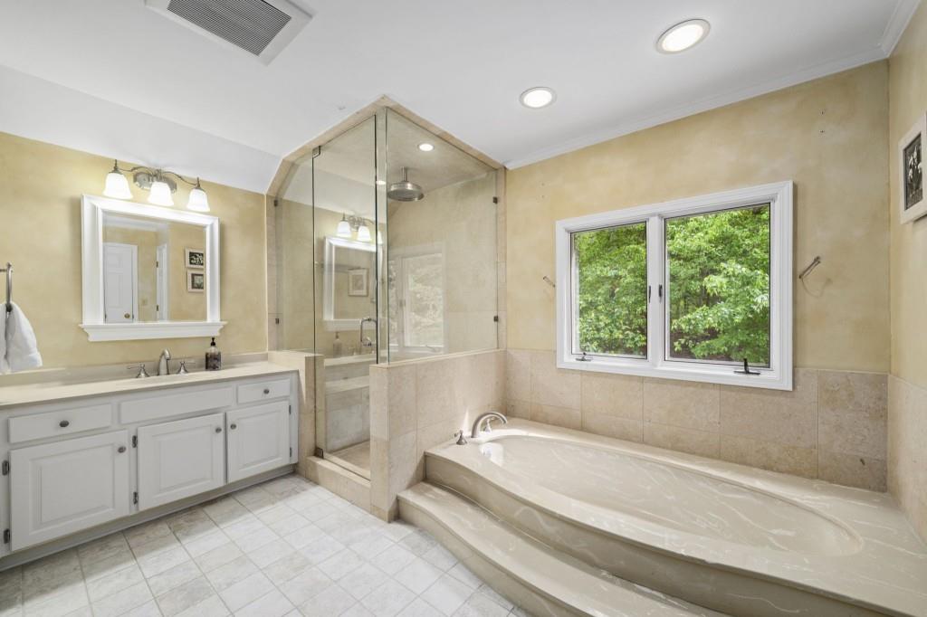 300 Waterpine Court Sandy Springs, GA 30350 - Photo 33 of 53 a spacious bathroom with a double vanity sink a large mirror and a bathtub