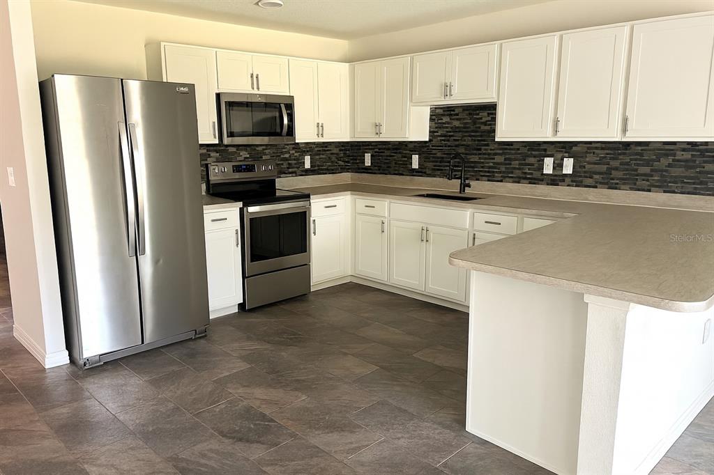 851 Alminar Avenue Southeast Palm Bay, FL 32909 - Photo 6 of 13 a kitchen with stainless steel appliances a refrigerator sink and microwave