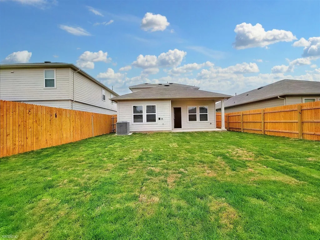 419 Sickle Loop Kyle, TX 78640 - Photo 33 of 35 A well-maintained lawn provides a spacious private yard, bordered by a secure wood fence.