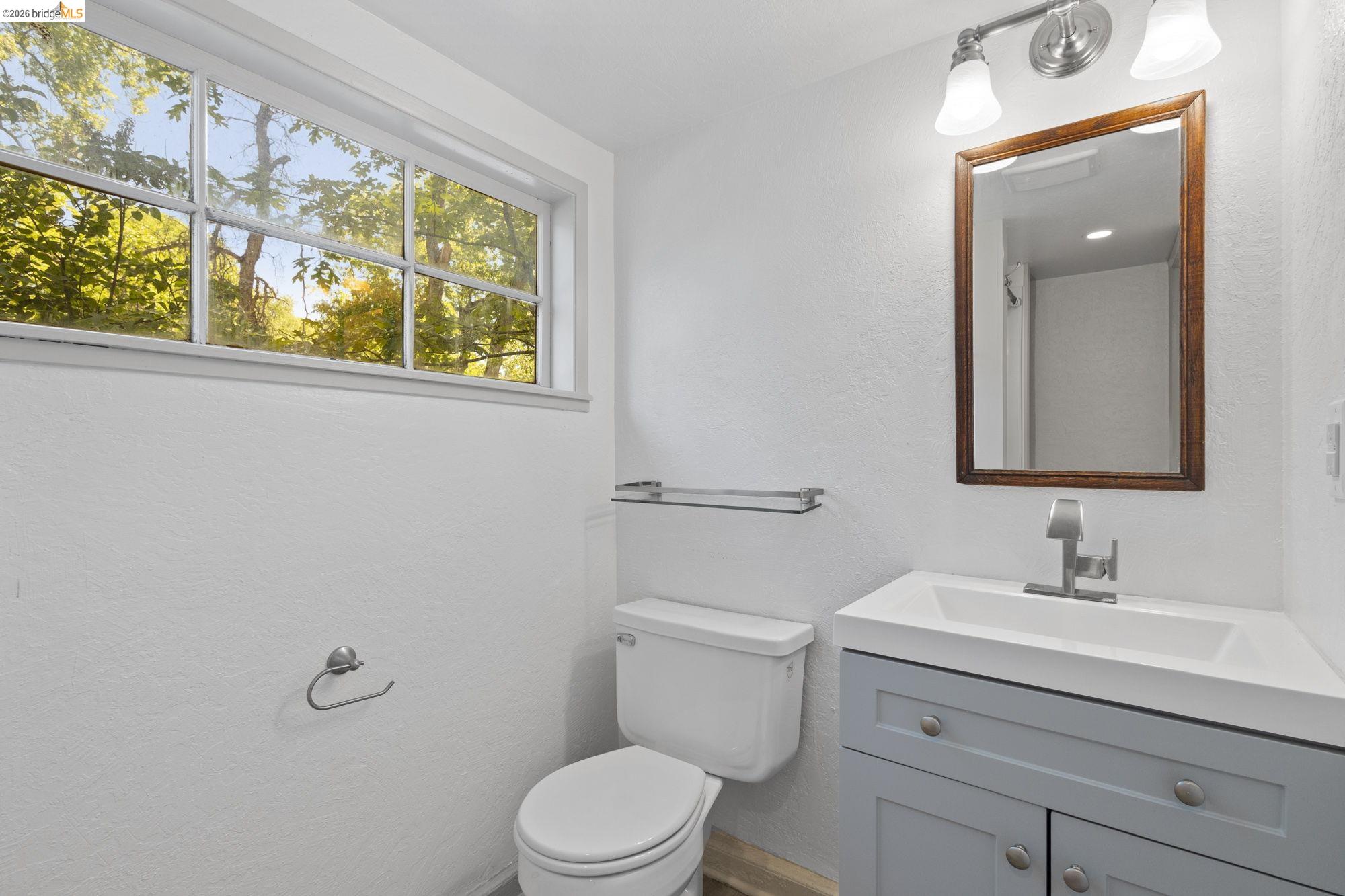 18363 Yosemite Road Tuolumne, CA 95379 - Photo 27 of 34 Bathroom featuring a single-pane window, white walls, built-in vanity with light blue cabinetry, integrated sink, and a framed mirror