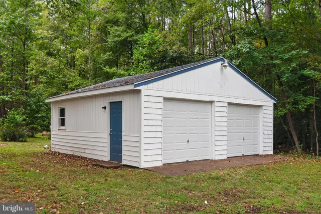 a view of a white house with a small yard and large tree