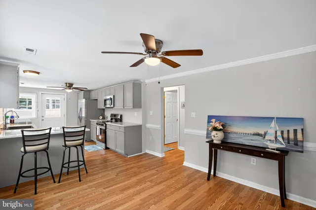 a living room with stainless steel appliances kitchen island hardwood floor and a kitchen view