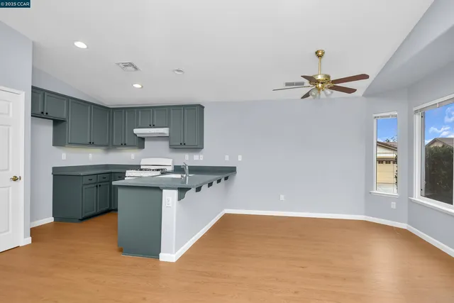 a kitchen with stainless steel appliances granite countertop a sink a stove a refrigerator cabinets and a window